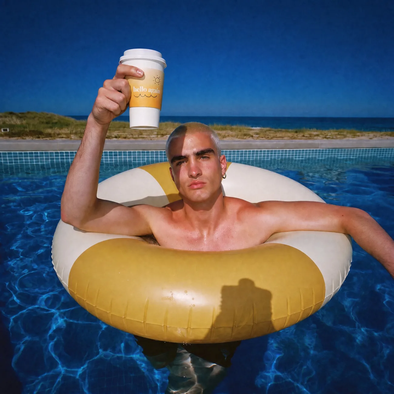 A man on a gold pool ring raising a Hello Again cup